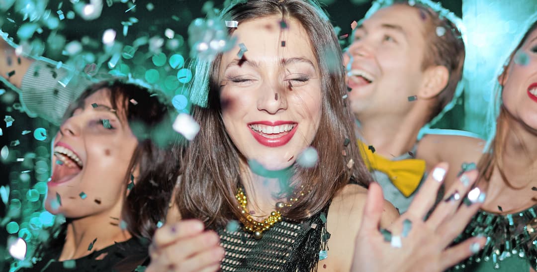 Vänner firar och dansar på fest med konfetti, musik och glad nattlivsstämning